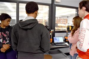 Students Looking at 3D printer printing their design